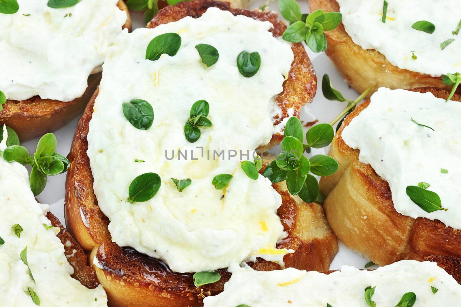 Bruschetta with ricotta cheese, lemon zest and thyme, drizzled with golden honey. Selective focus on center Bruschetta and some blur on lower portion of image.
