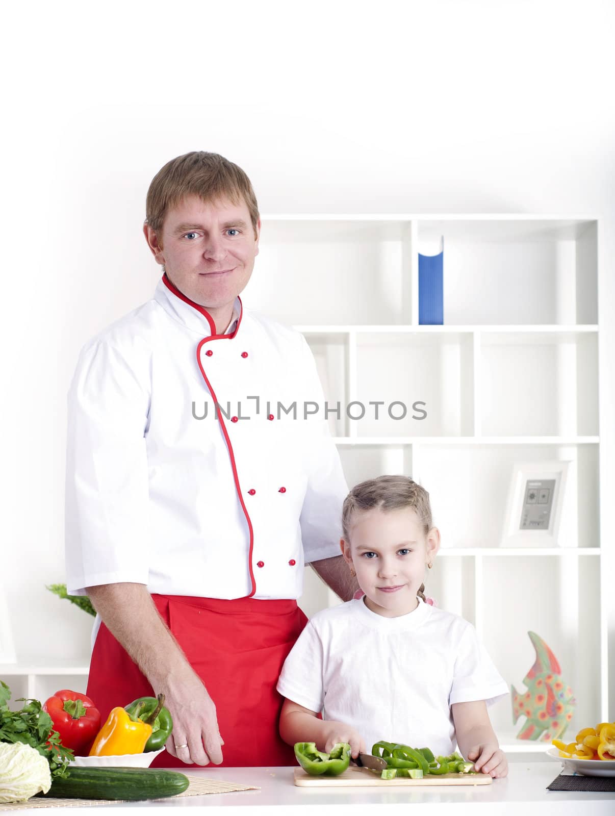 portrait of father and daughter cooking salad together in the kitchen