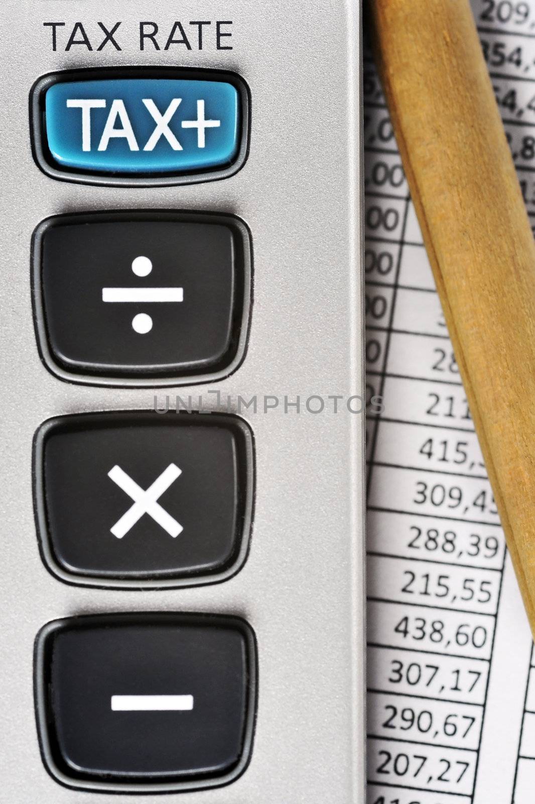 Detail of calculator, focusing the TAX key, next to a sheet of paper with numbers and a pencil.