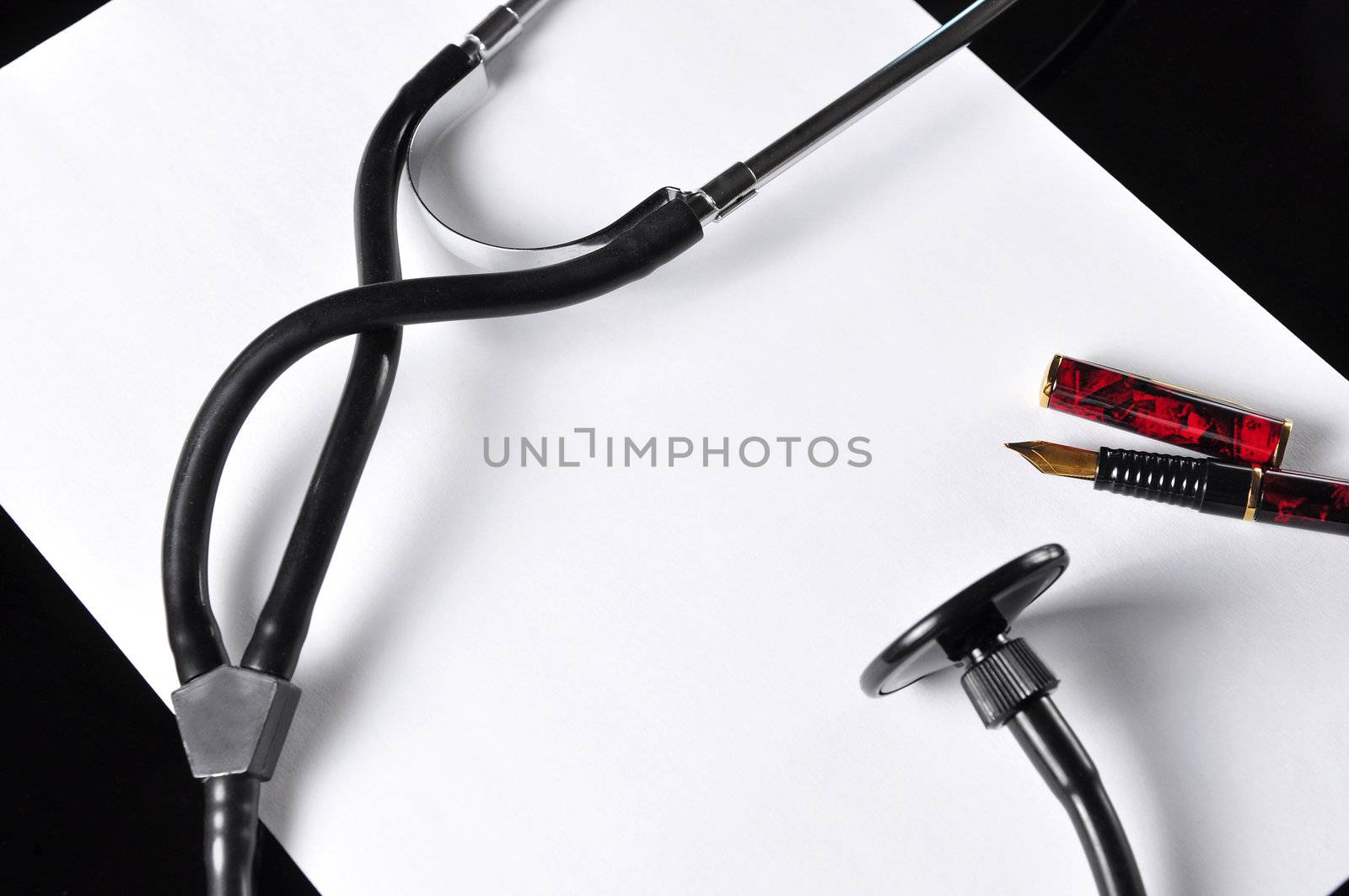 A white piece of paper, a stethoscope and a fountain pen on a doctor's table