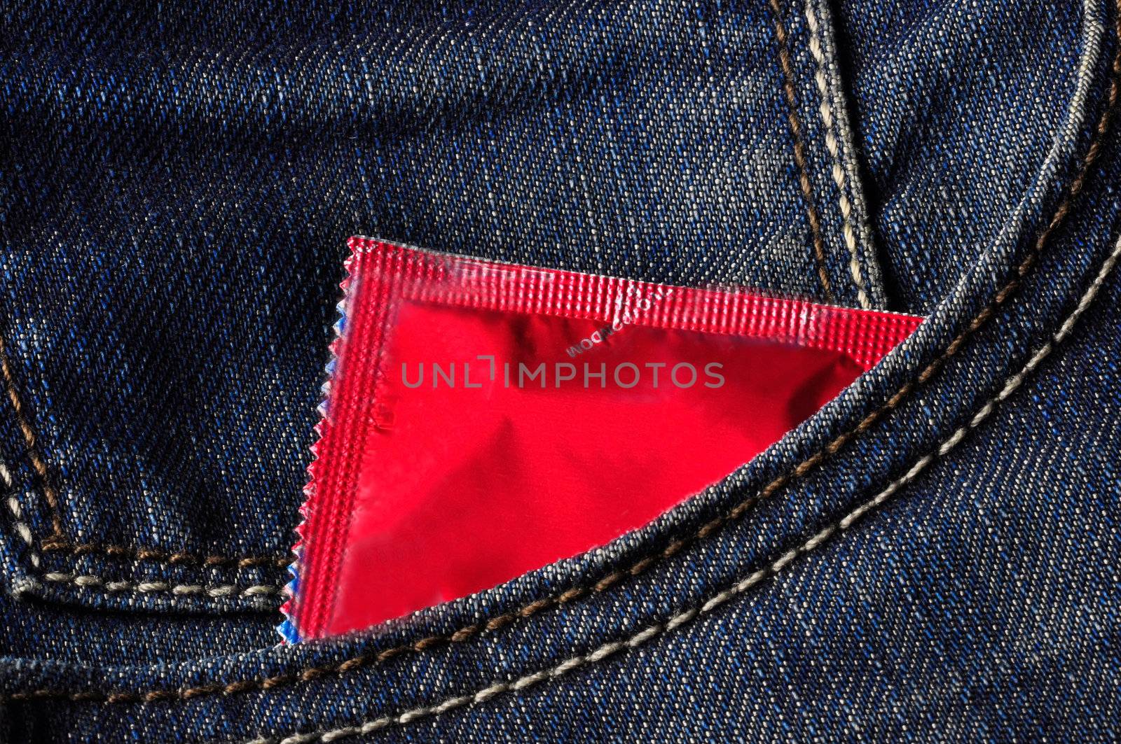 A red condom inside a jeans pocket