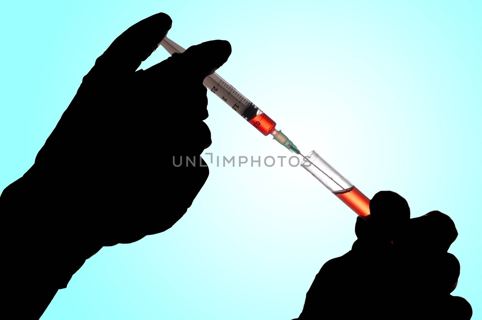 Hand holding a syringe and taking a blood sample from a tube for analysis