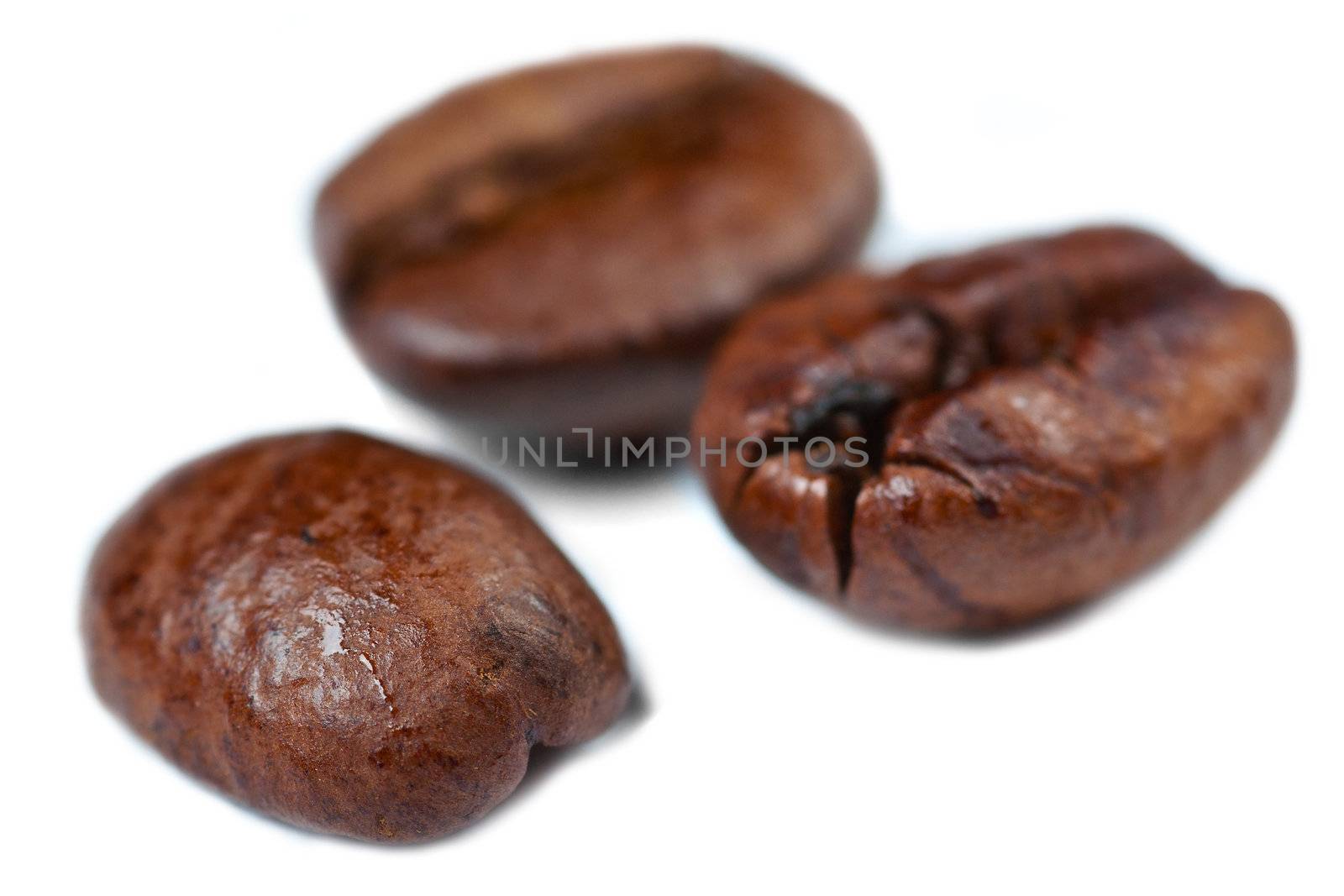 Three coffee beans on a white background with low depth of field.
