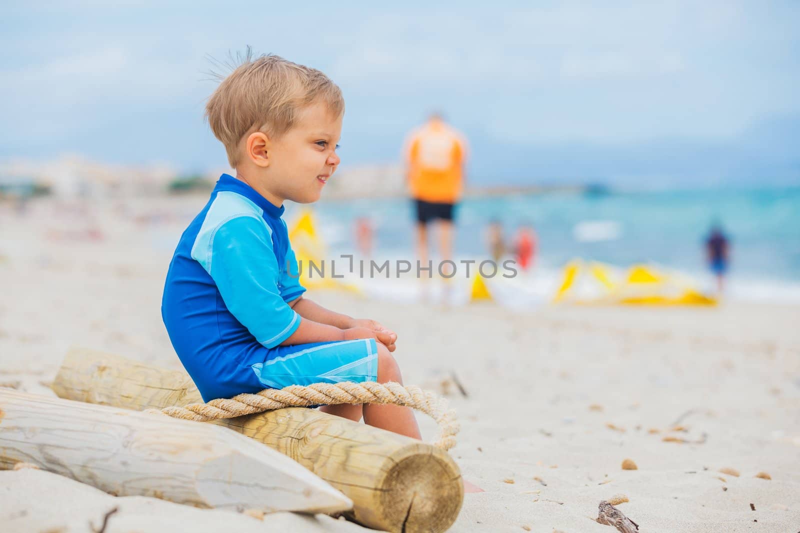 Cute 2 years old boy looking at kiting on tropical beach