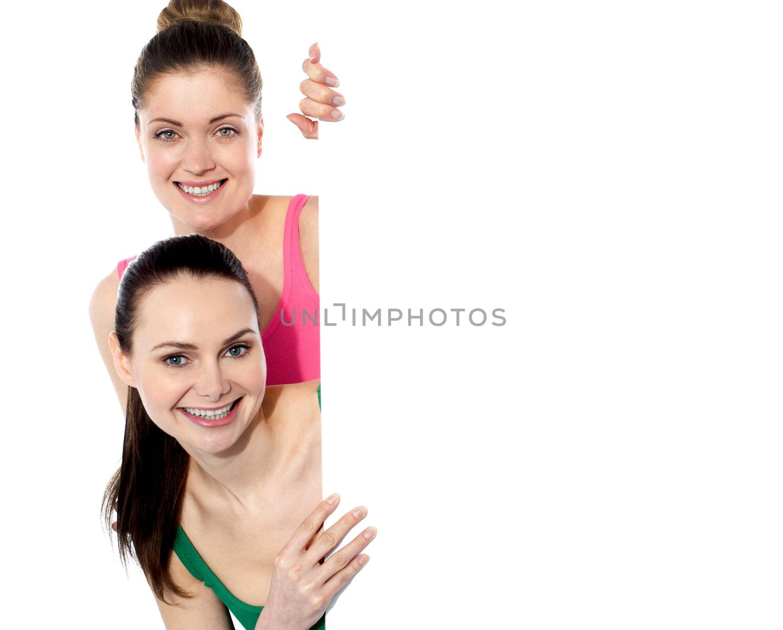 Two attractive girls holding blank whiteboard, smiling at camera