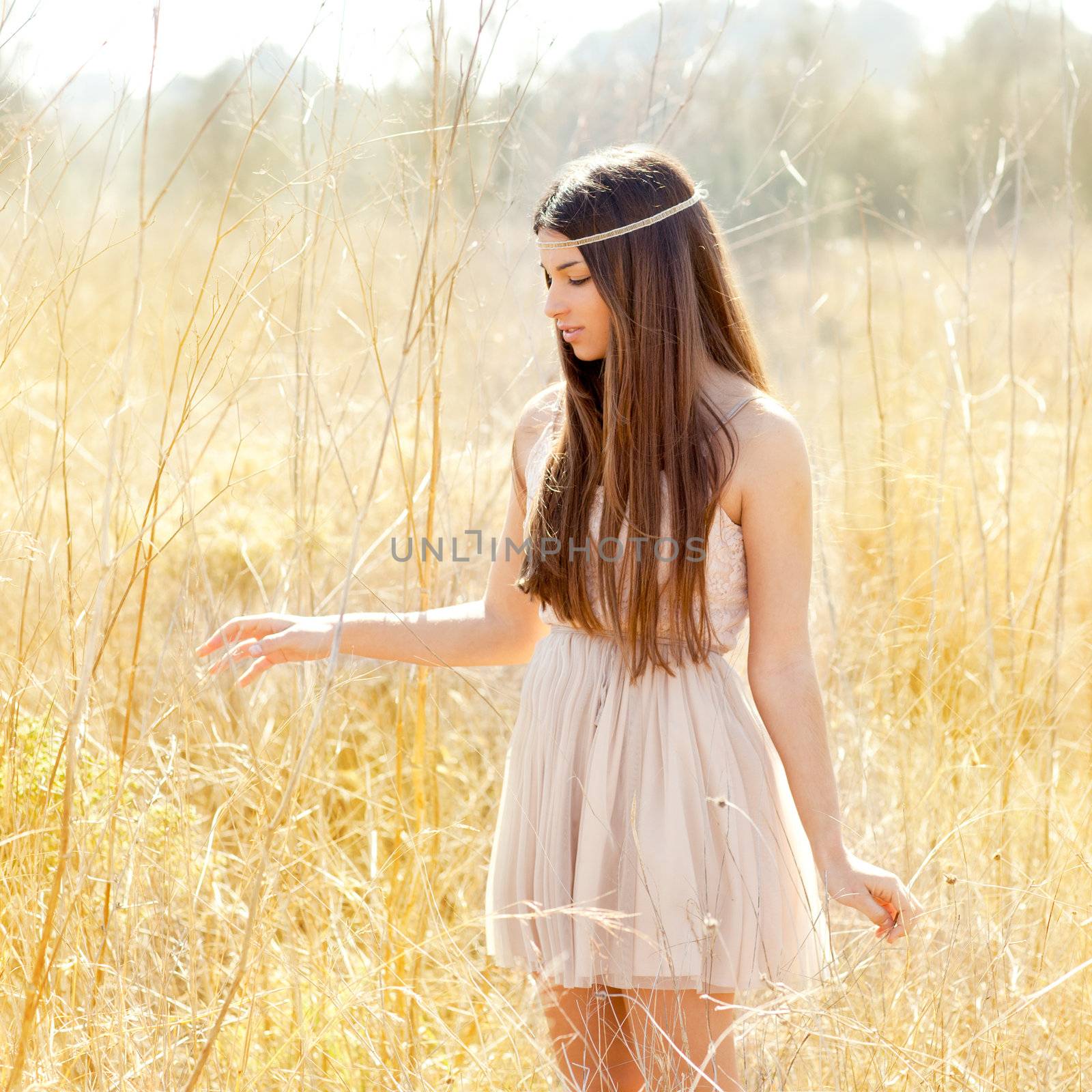 Asian indian woman walking in golden dried grass field