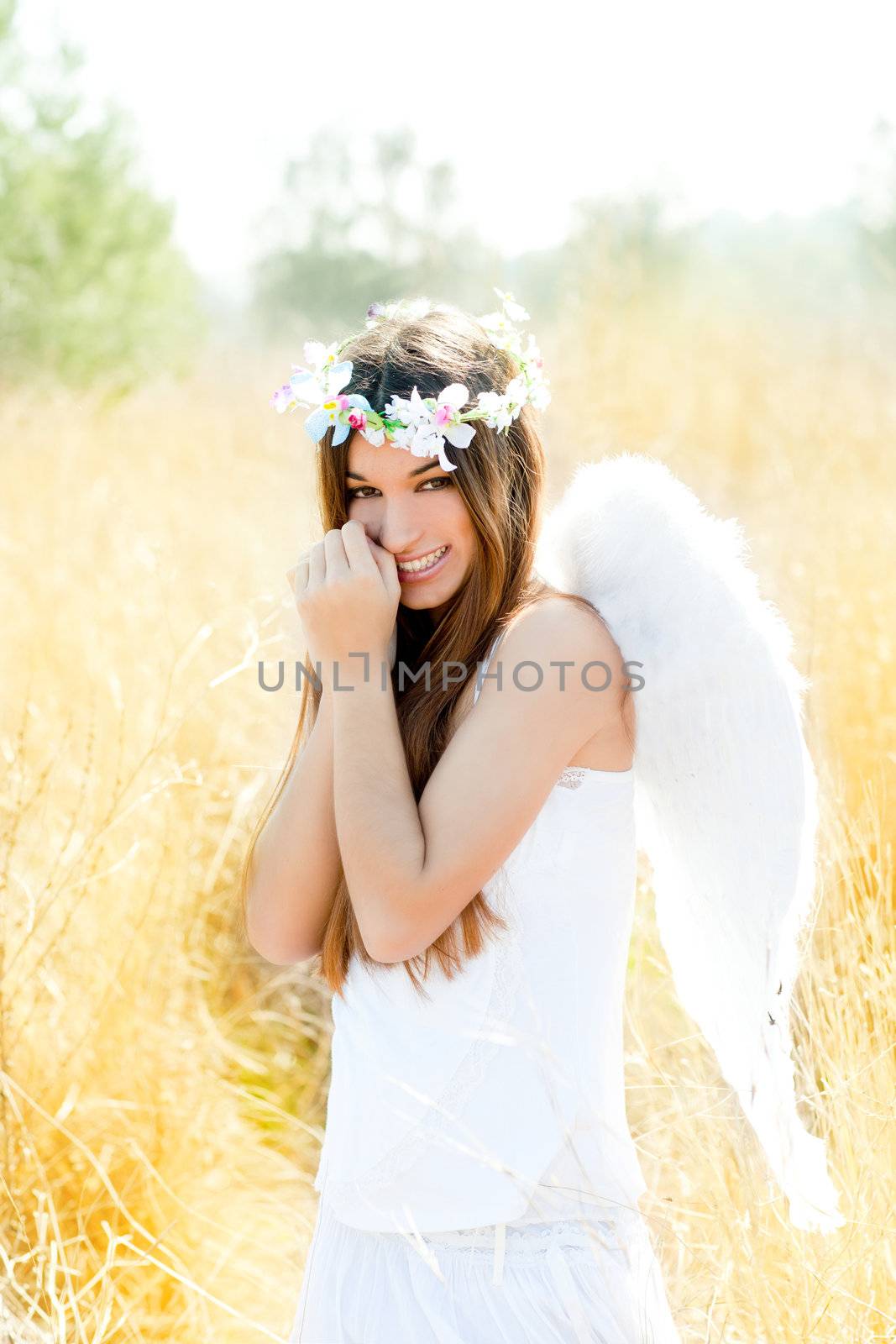 Angel etchnic woman in golden field with feather white wings and flowers crown