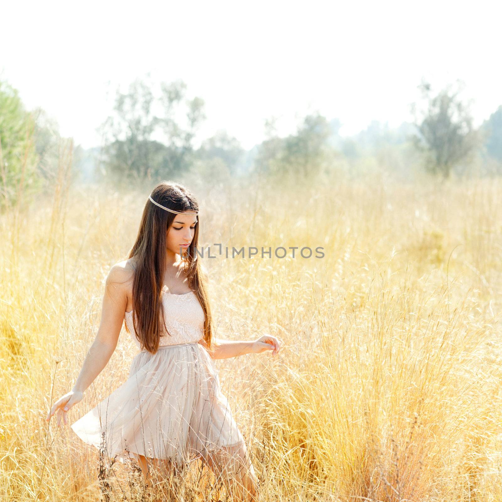 Asian indian woman walking in golden dried grass field