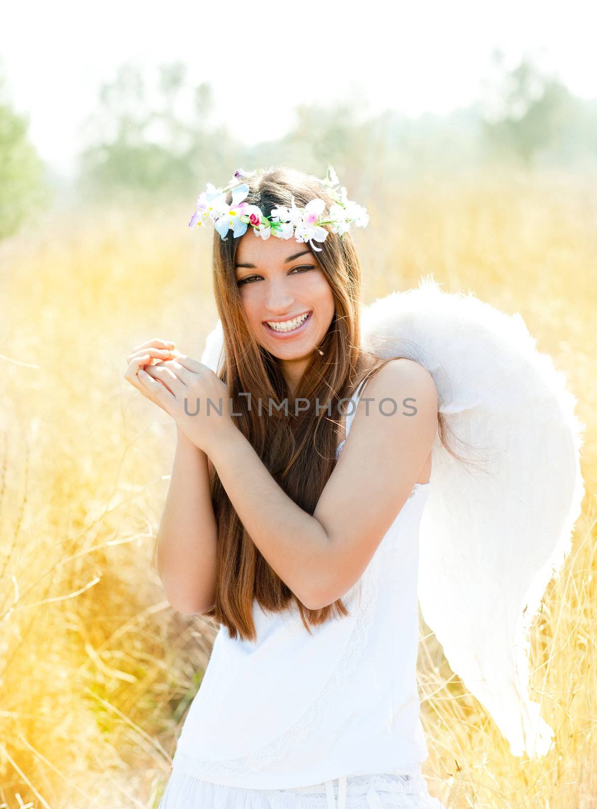 Angel etchnic woman in golden field with feather white wings and flowers crown