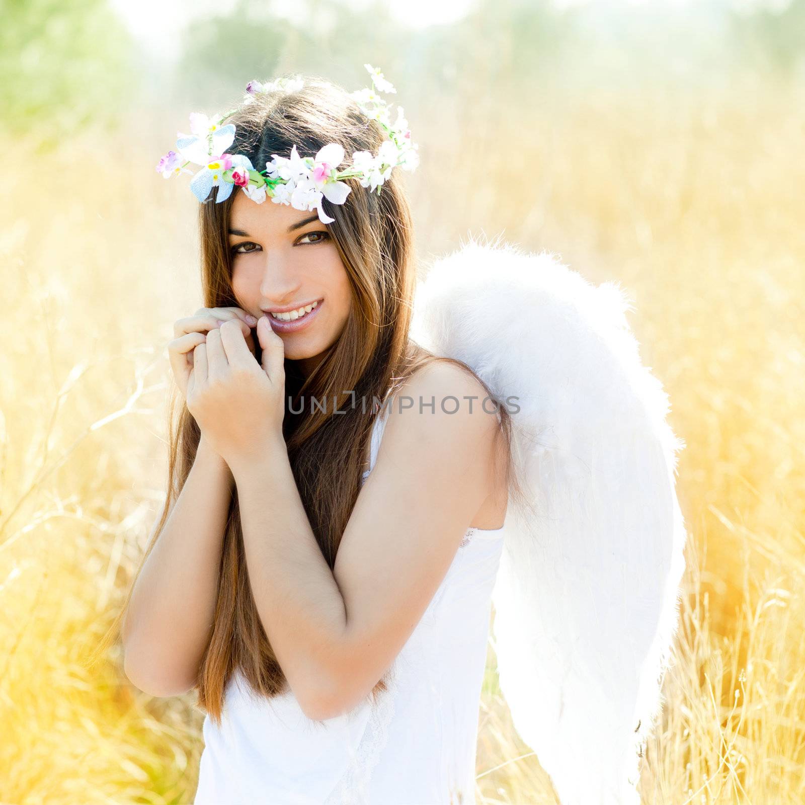 Angel etchnic woman in golden field with feather white wings and flowers crown