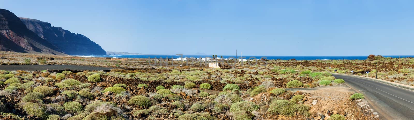 Empty road crossing the lava in the mountain, volcano backround. Panorama. Lanzarote, Canary islands, Spain