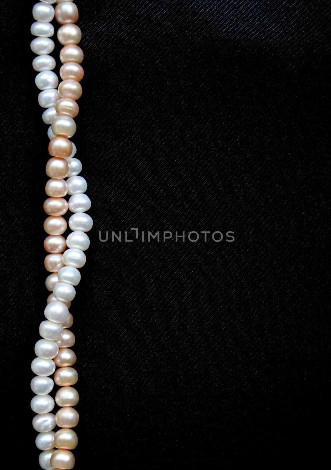 White and pink pearls on the black silk can use as background

