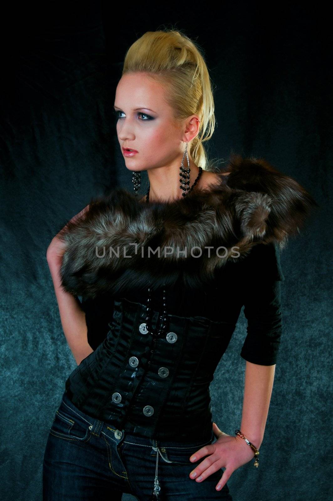 Young blond woman with fur, professional hair and makeup, on dark background.