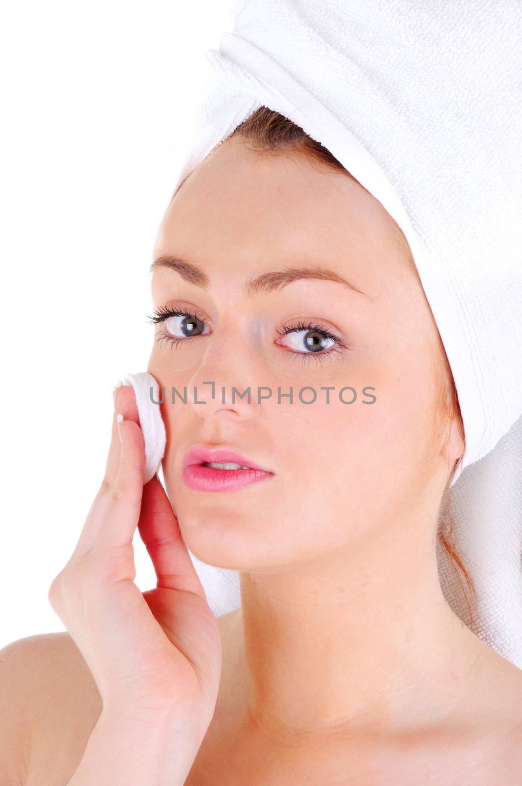 Young woman with white tower and nice manicure is cleaning her face, on white background