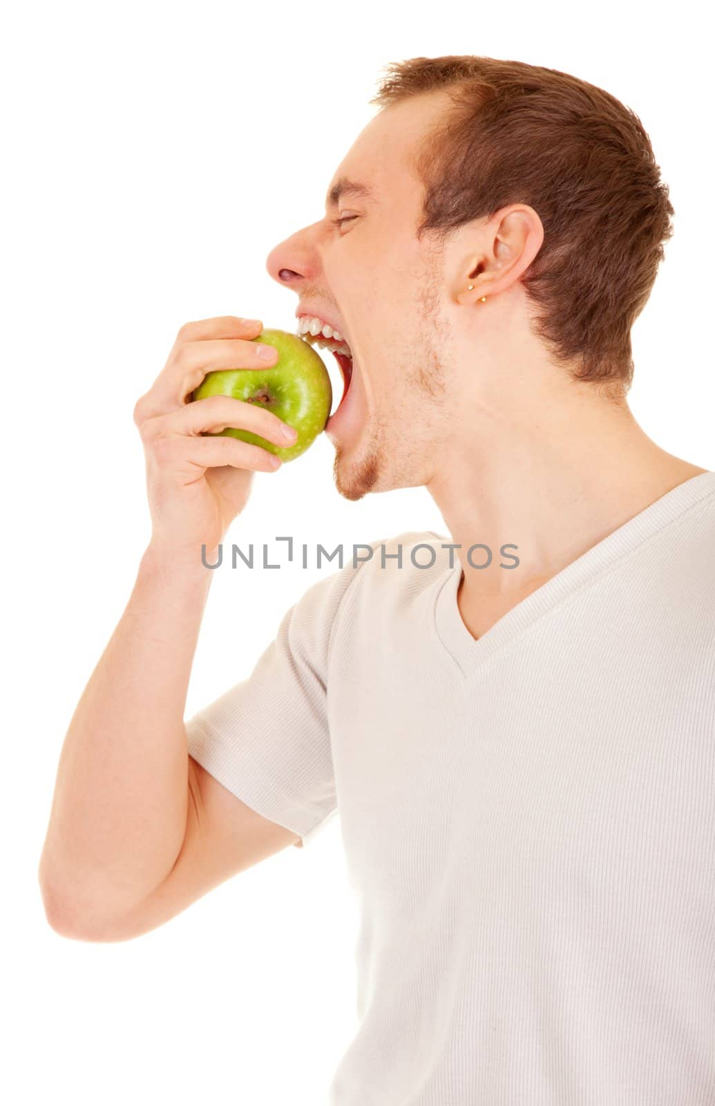 Young handsome man is biting a green apple on his palm. On white background.
