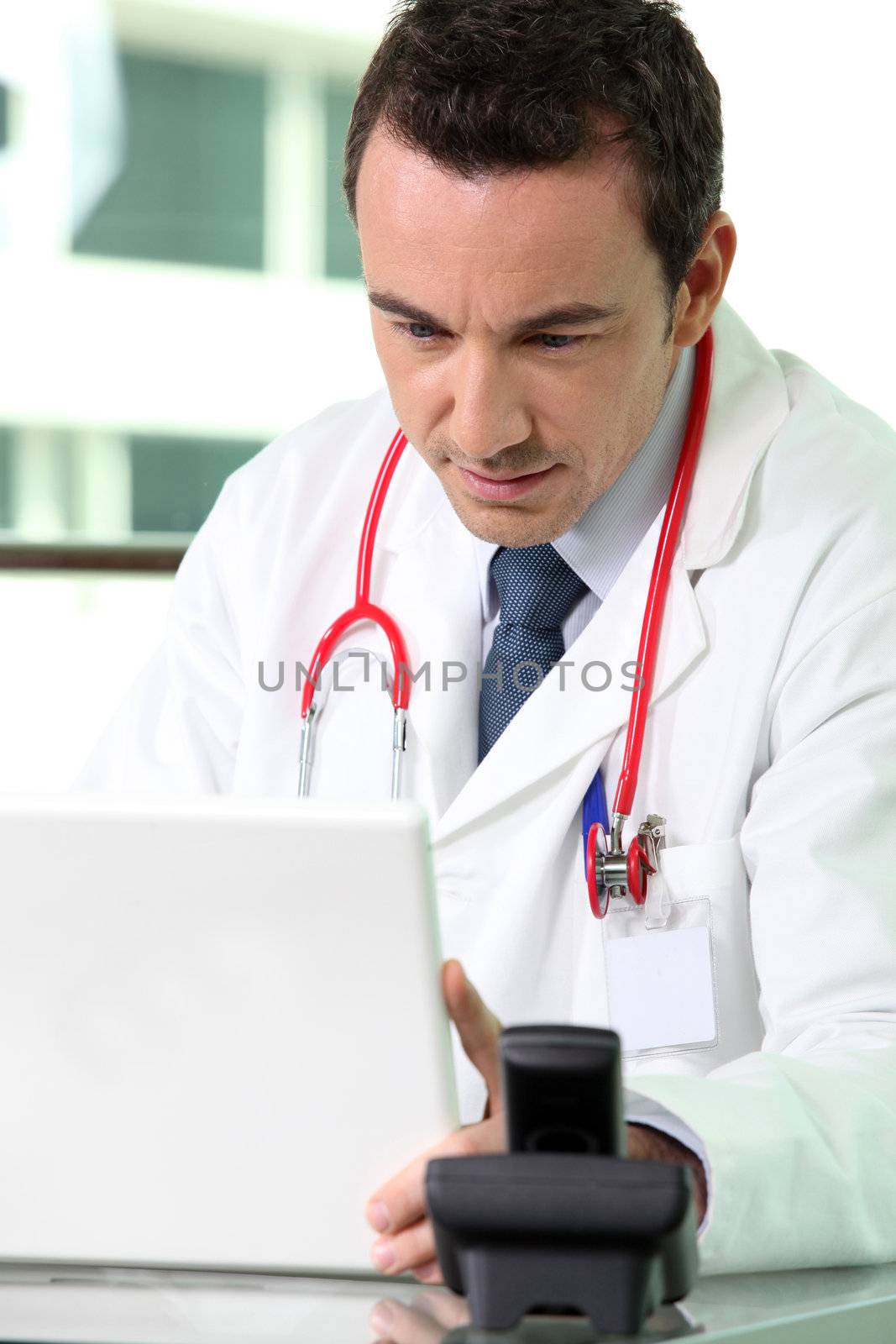 A doctor looking at his laptop by phovoir