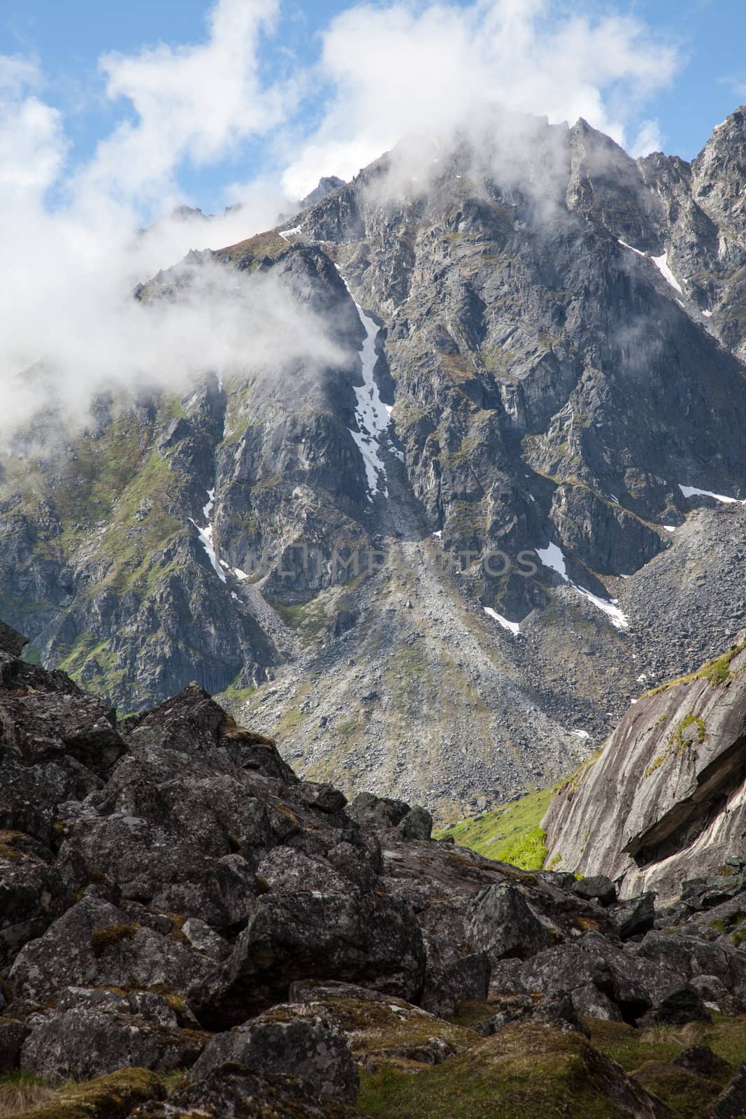 Rugged mountain peaks lie shrouded in clouds on a summer day