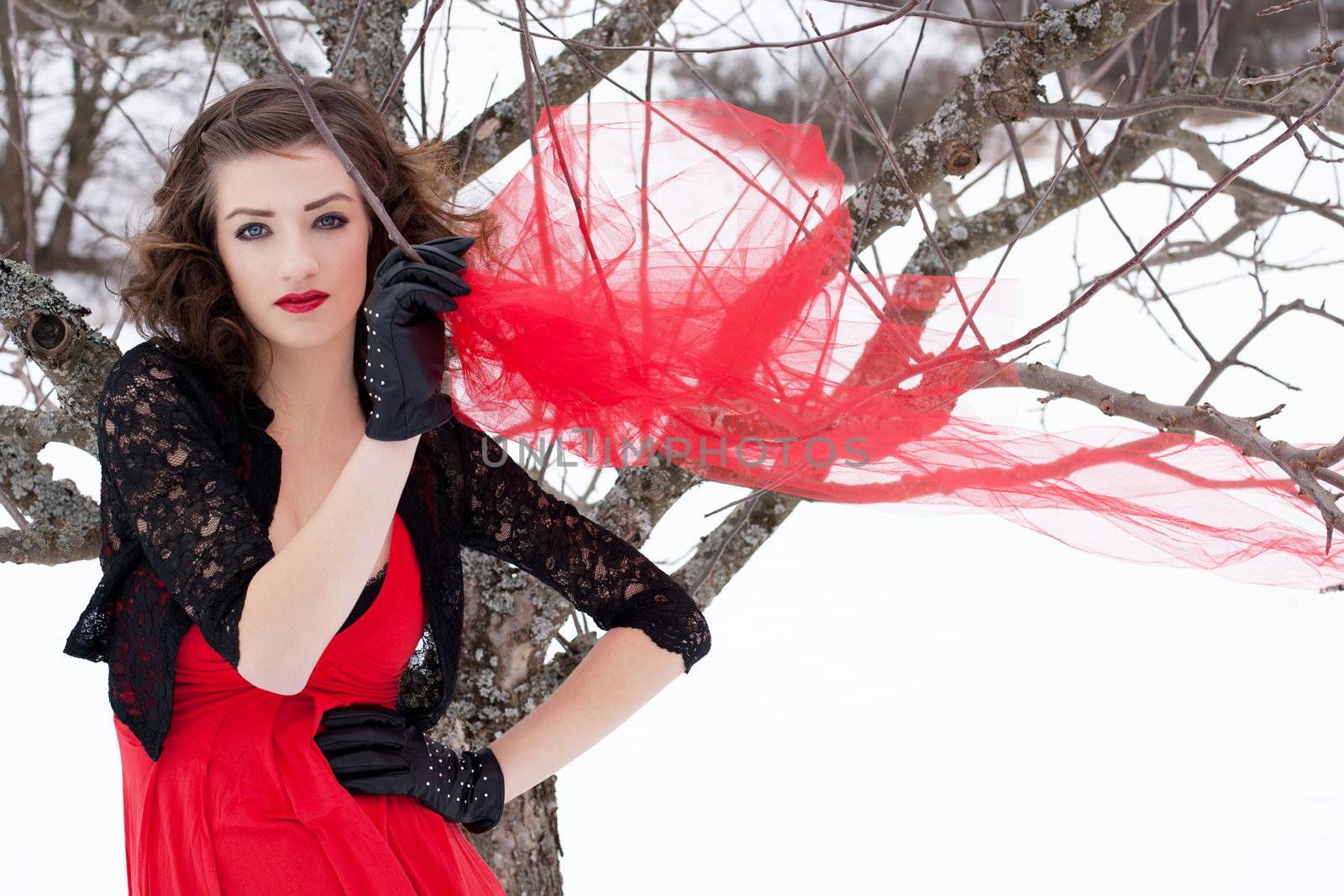 Beautiful woman with dark hair and red lips in white snow