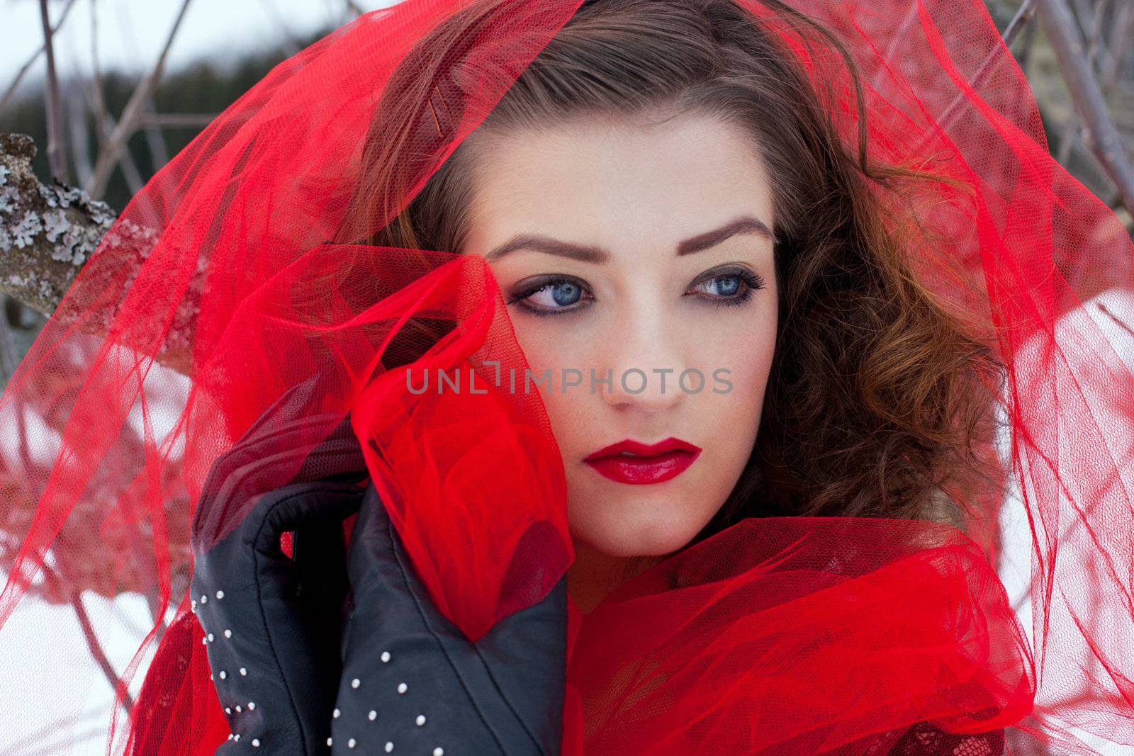 Beautiful woman with dark hair and red lips in white snow