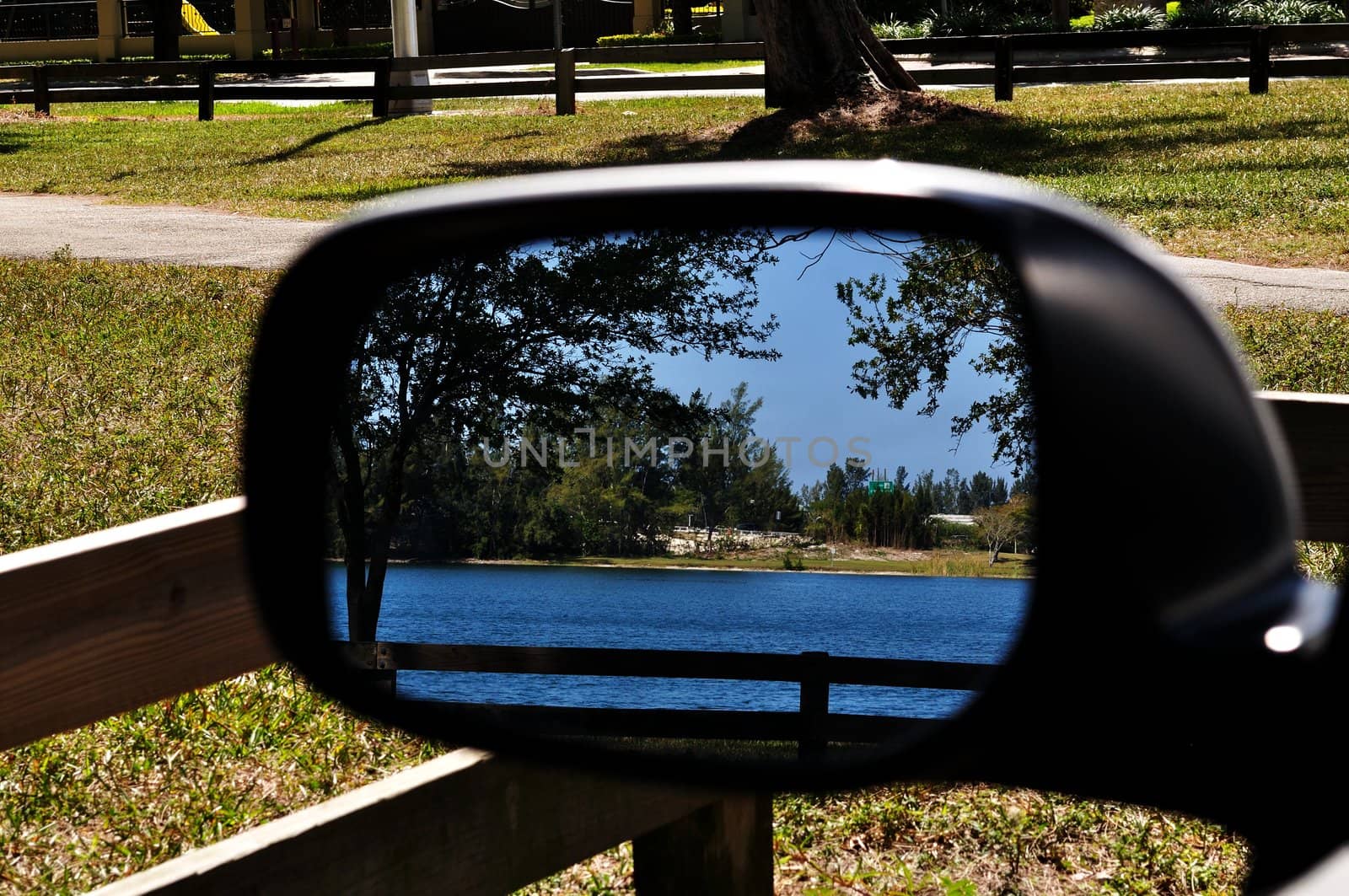 Lake reflected in the sideview mirror of a parked car.