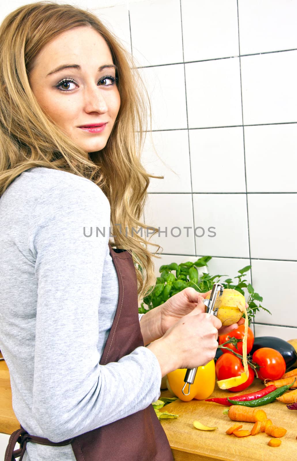 young beautiful housewife is cooking with fresh vegetables by juniart