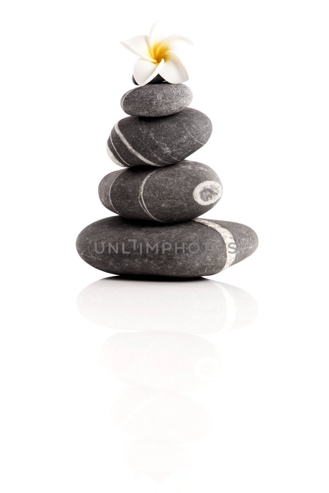 Stones pyramid with a plumeria flower, isolated on white background