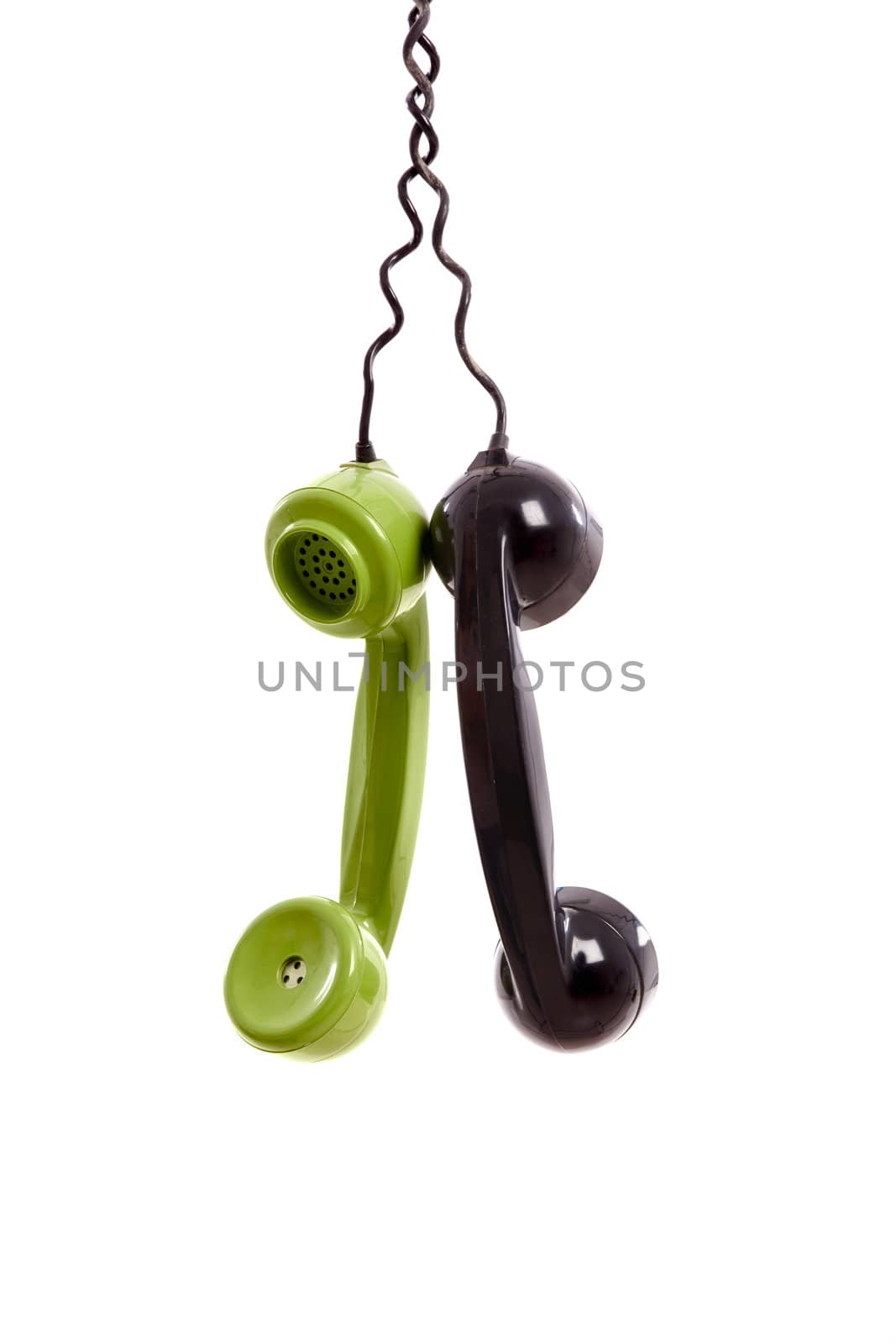 Two Handset piece from old phones suspended by the phone cord, isolated on white background