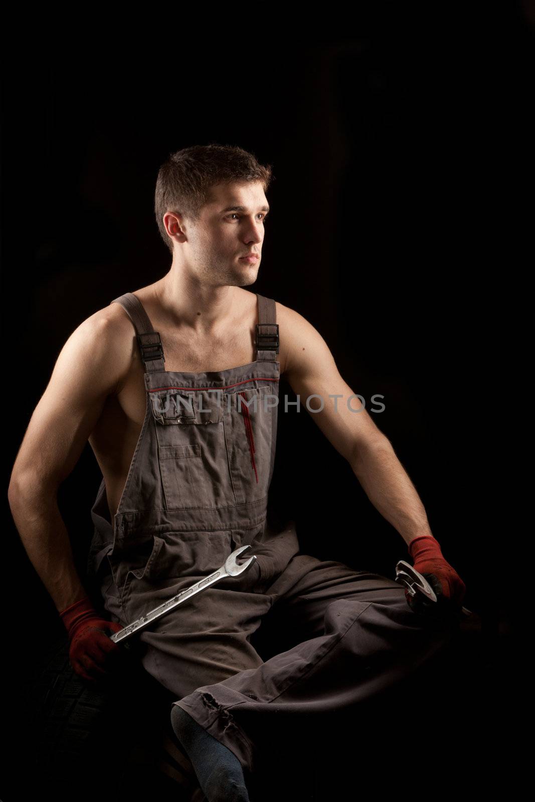 repairman with big wrench over black background