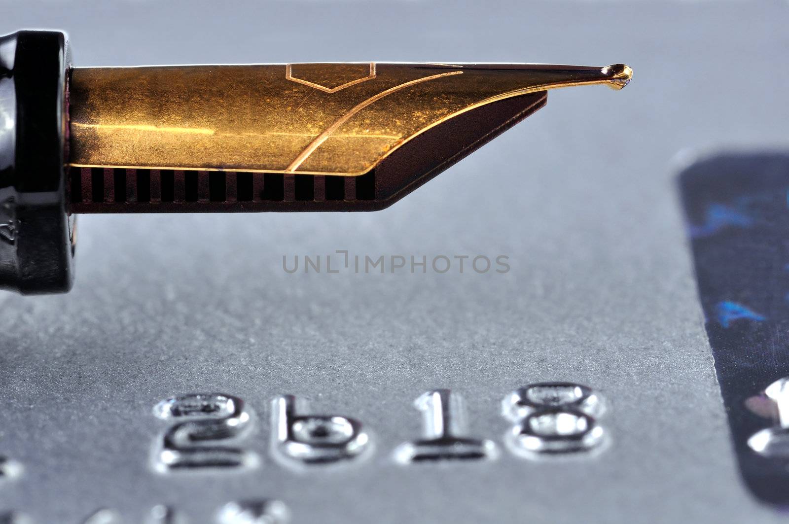 Closeup of a credit card with a golden fountain pen on top of it