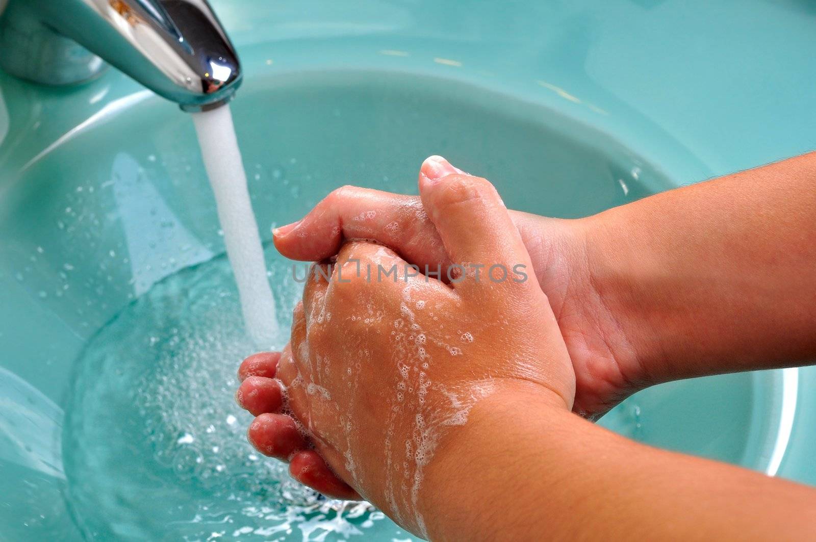Hands being washed in a green sink