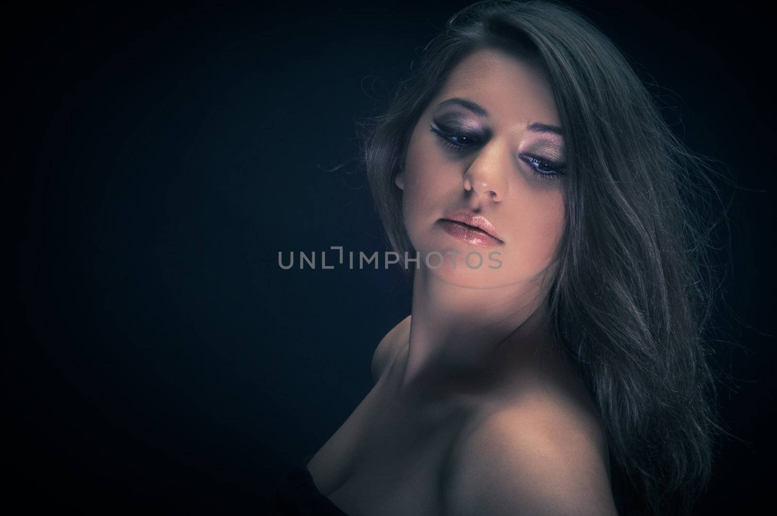 Girl with long hair in the studio against dark background