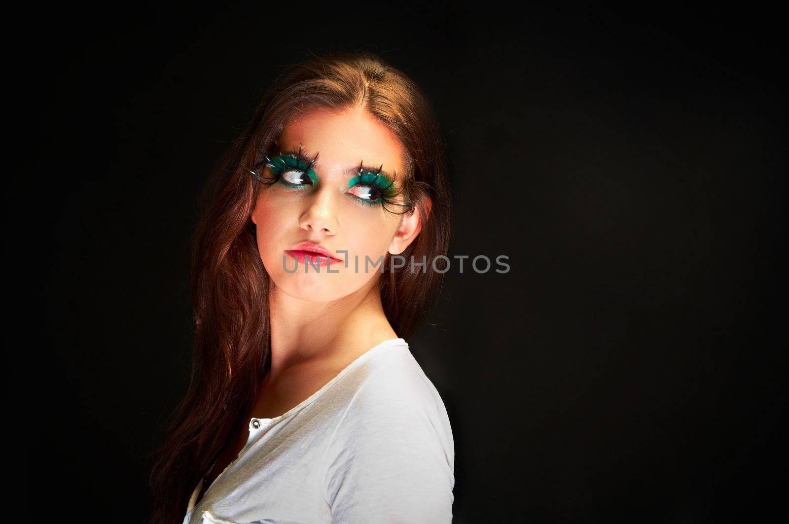 Young wiman in the studio with extreme makeup against dark background