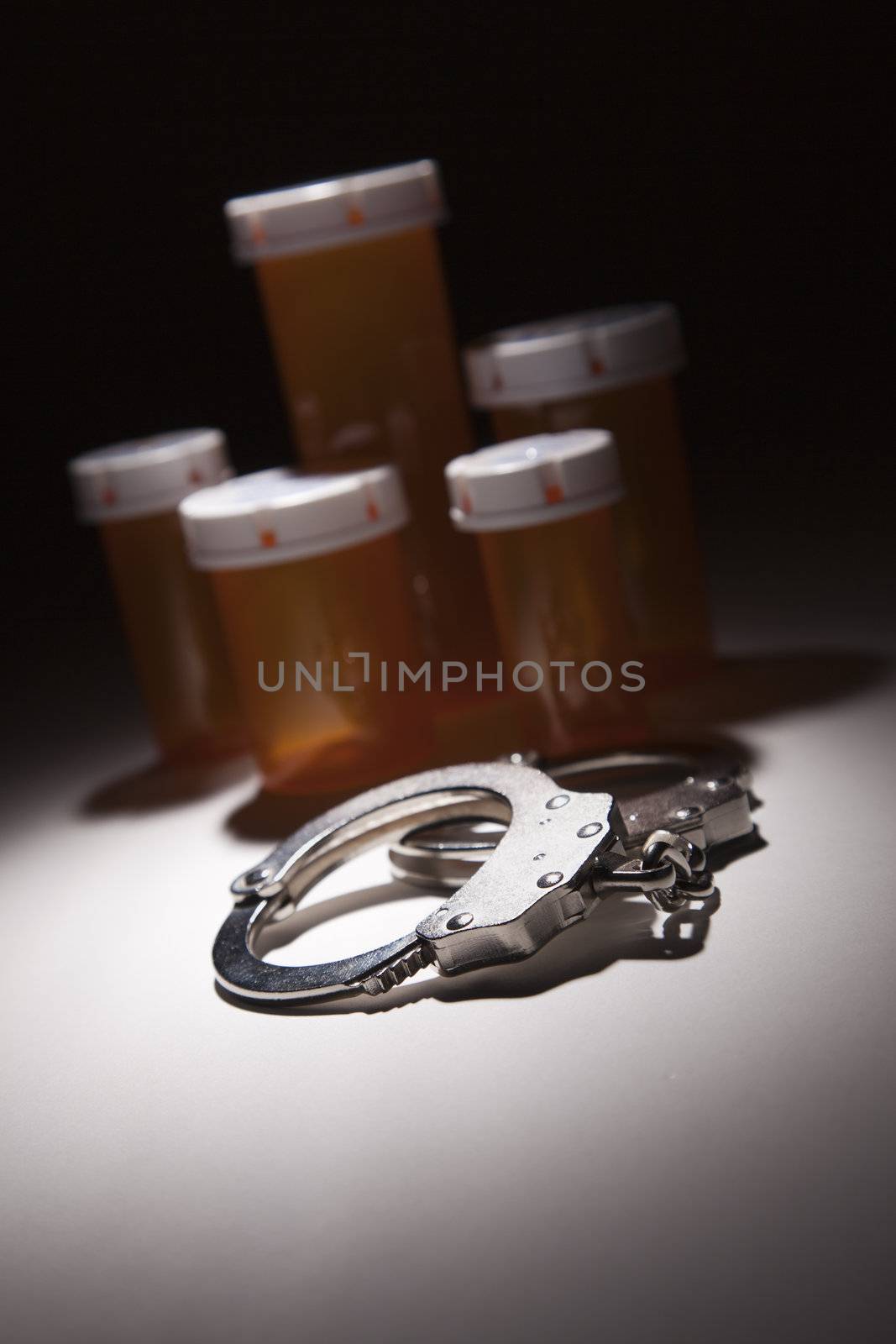 Handcuffs, Medicine Bottle and Pills Under Spot Light by Feverpitched