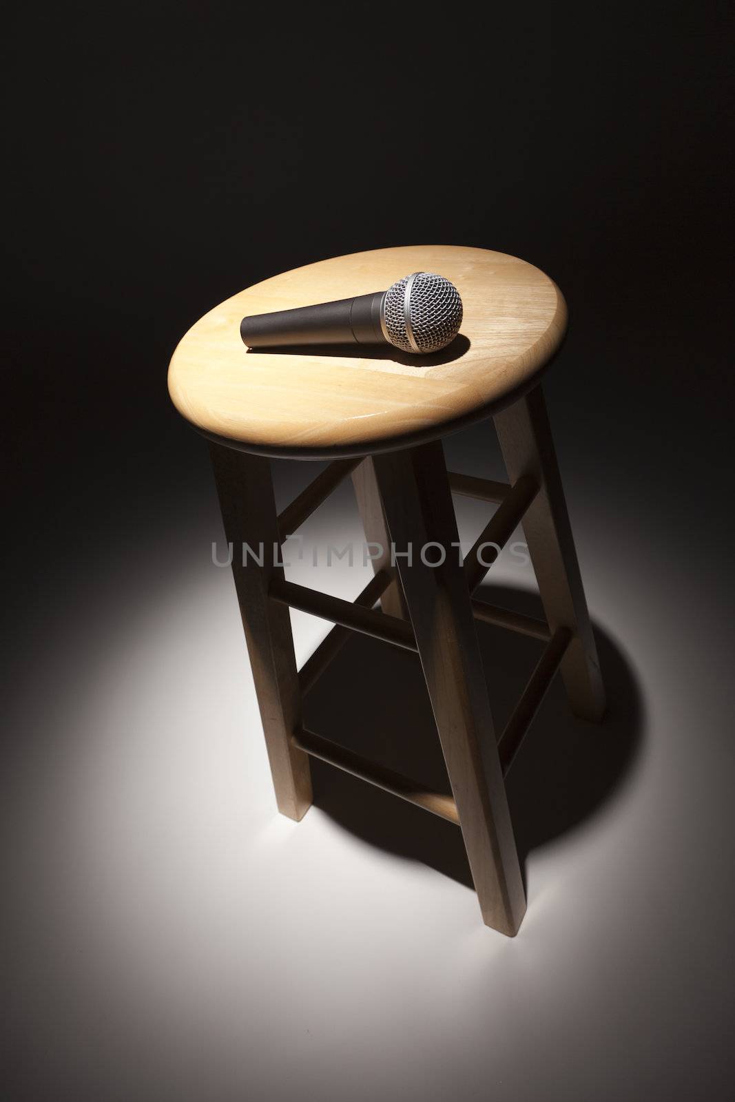 Microphone Laying on Wooden Stool Under Spotlight by Feverpitched