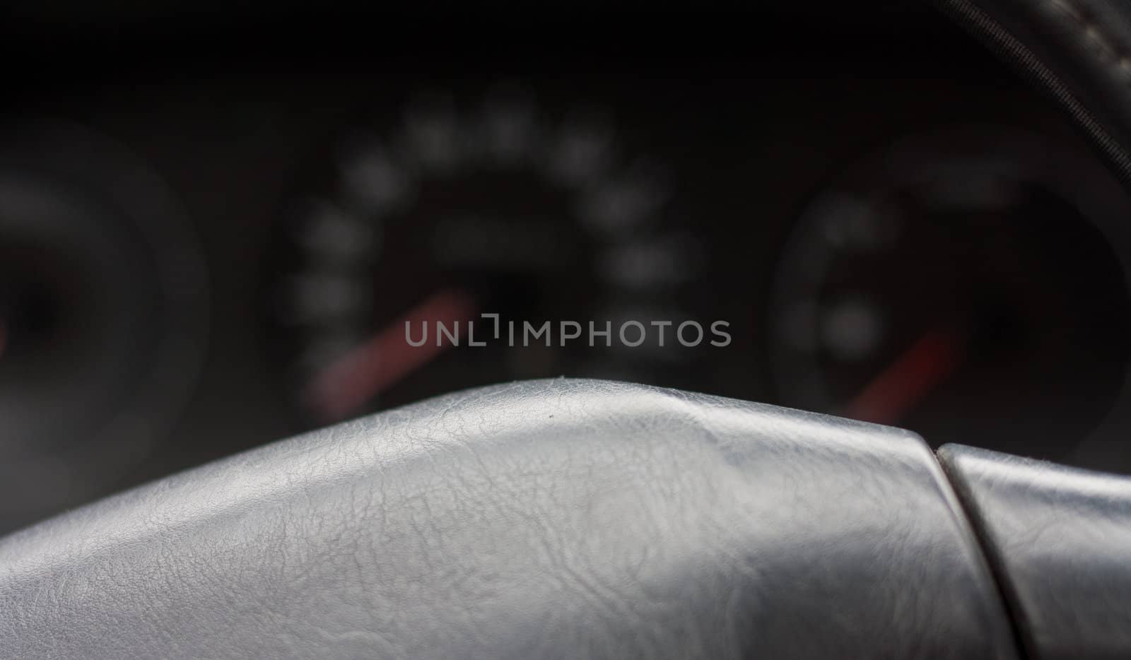 Closeup macro shot of a steering wheel and a car speedometer