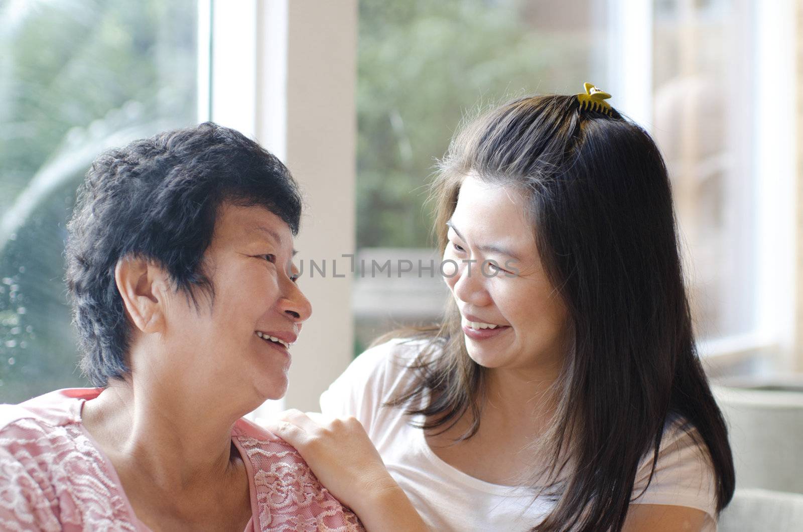 Asian family, adult daughter having conversation with senior mother indoor.
