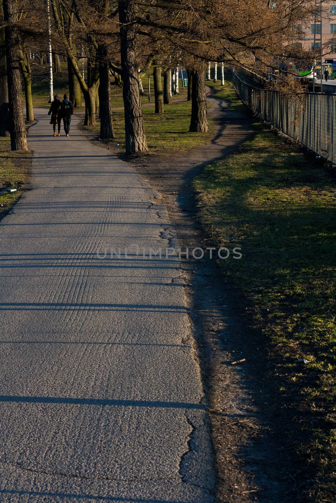 Park road going near a railroad with two people walking