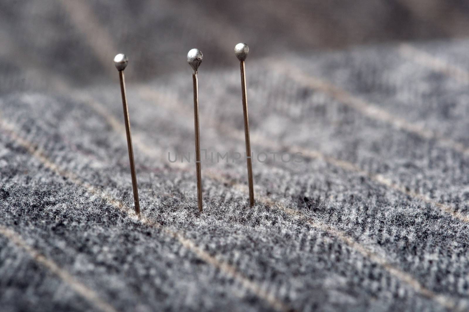 Closeup of three pins on a grey stripesd suit