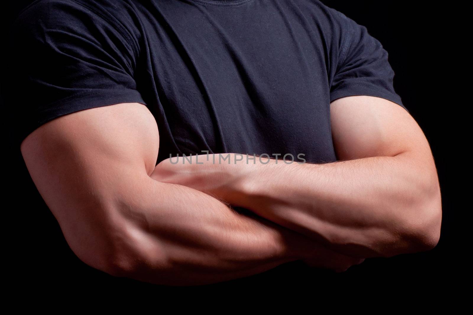 Male security guard with strong arms crossed in a dark background
