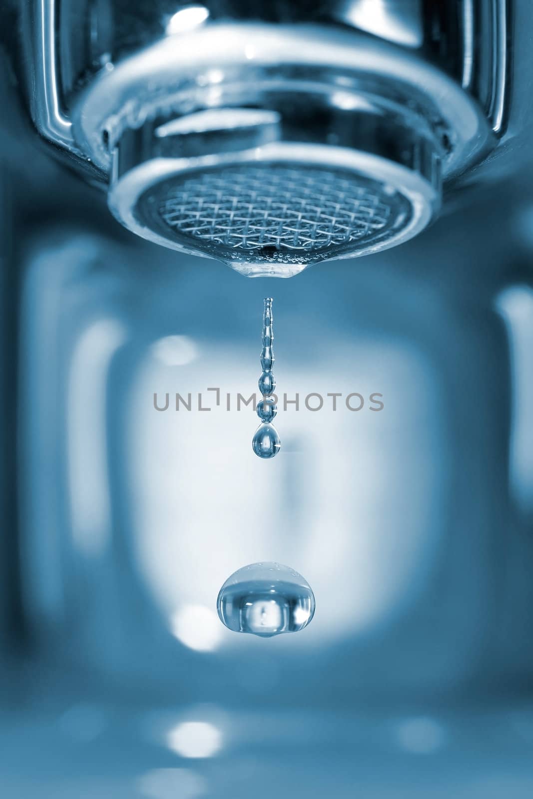 Water drop falling form a faucet in a blue bathroom, low depth of field