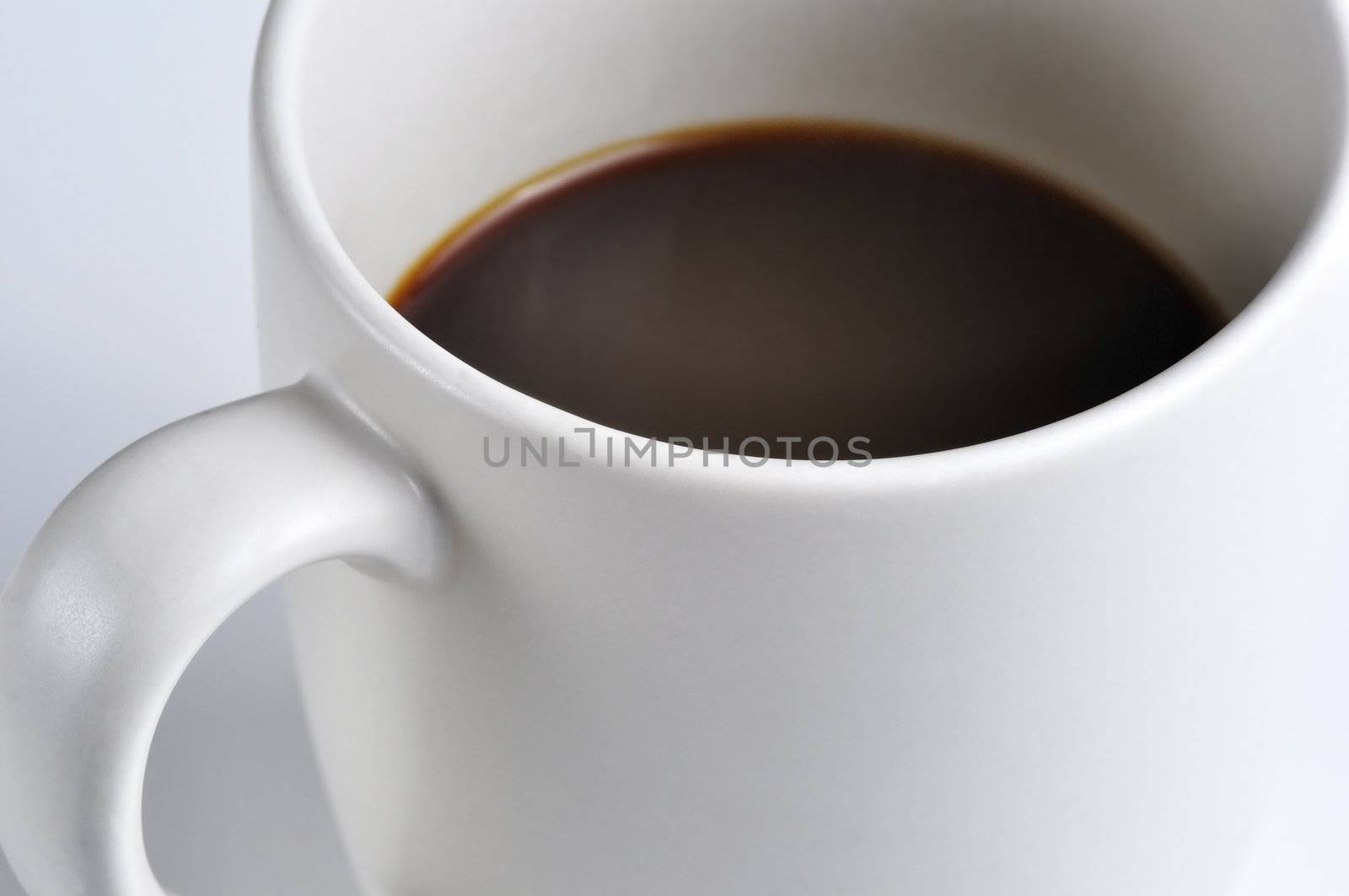 Coffee cup with coffee in a light grey background, soft focus, some grain added