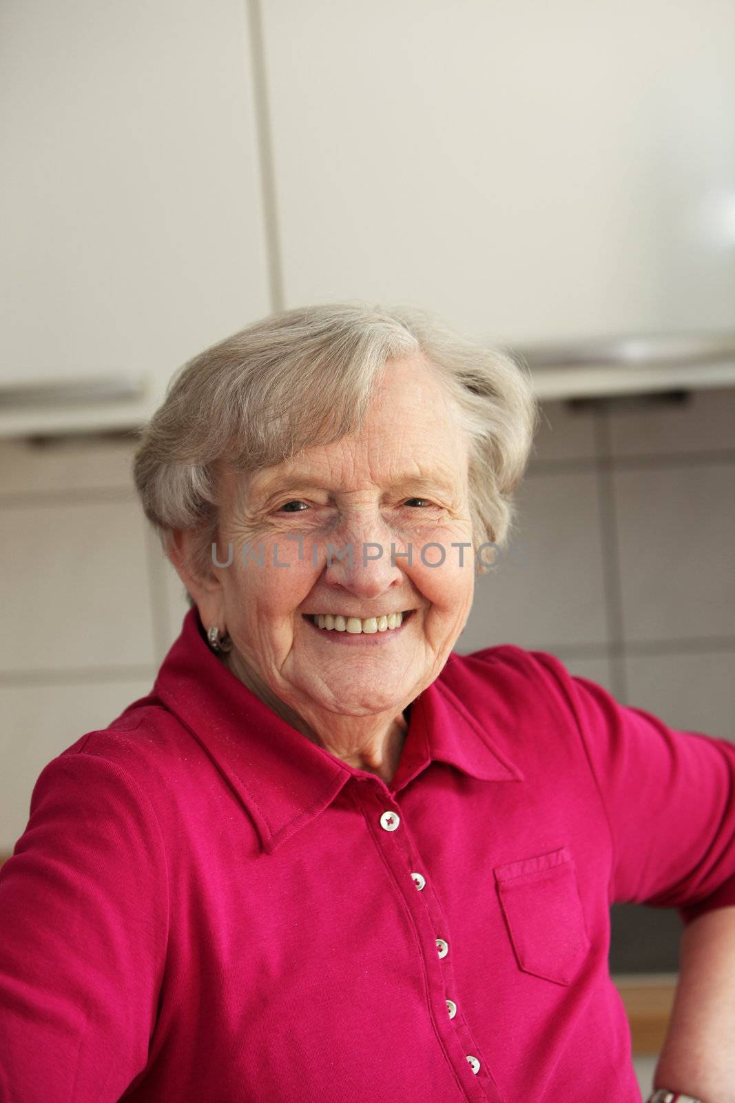 Elderly grey-haired retired lady with a beautiful smile relaxing in a kitchen chair