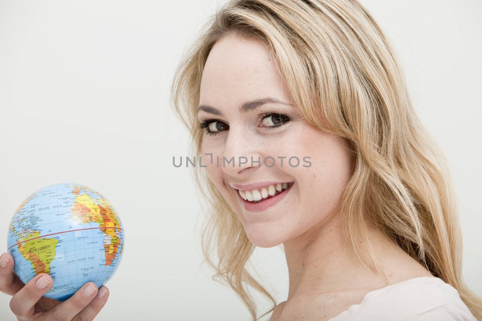 smiling blonde woman holding a globe on a white background