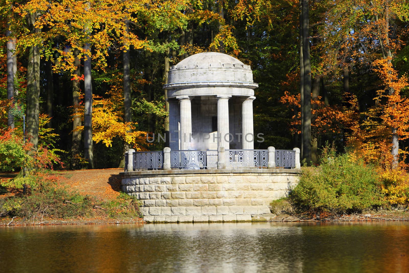 Ornamental gazebo on the waters edge at a lake surrounded by autumn or fall foliage
