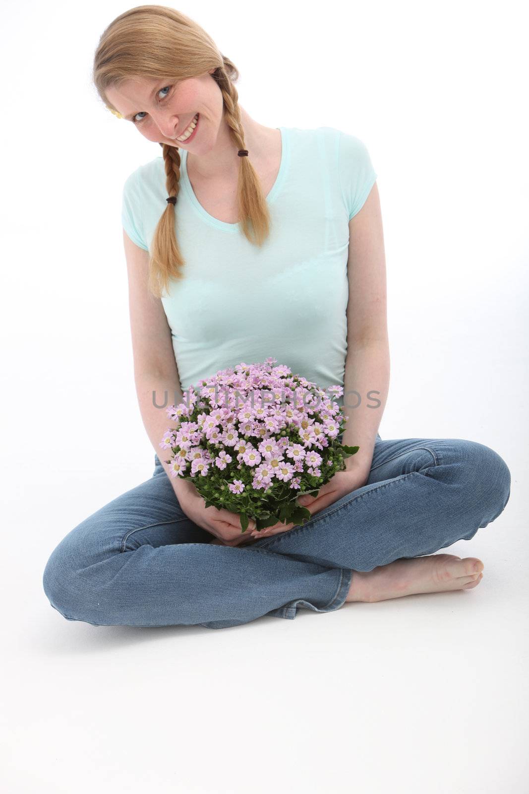 Attractive smiling woman sitting and holding flowers on white background