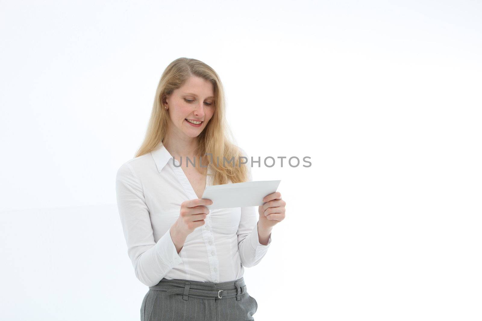 Attractive blonde woman concentrating while reading a letter she is holding in her hands isolated on white