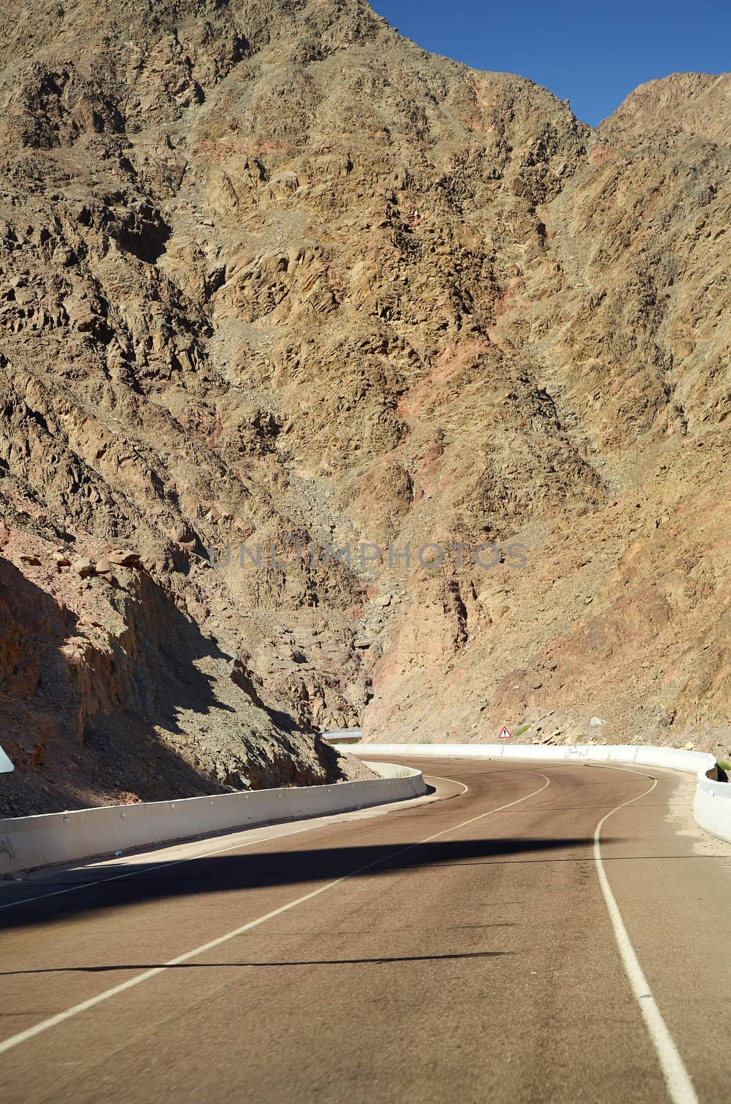 Empty road crossing an arid mountain in desert