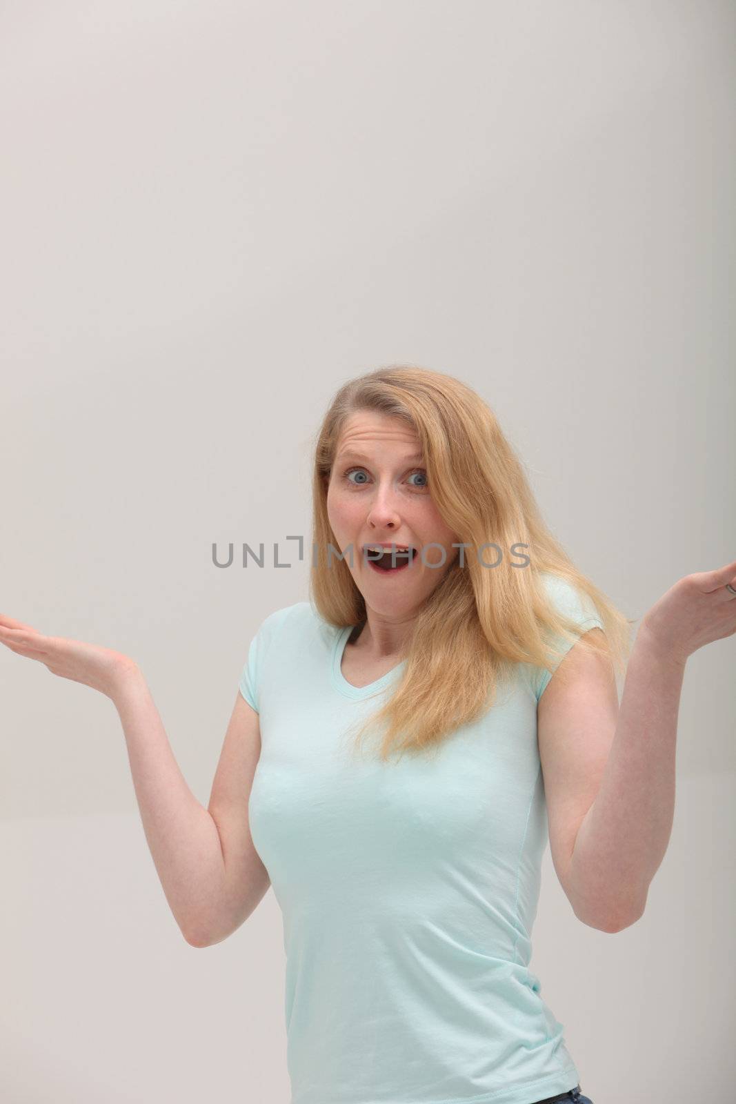 Woman shrugging her shoulders and raising her hands in the air in ignorance or indifference