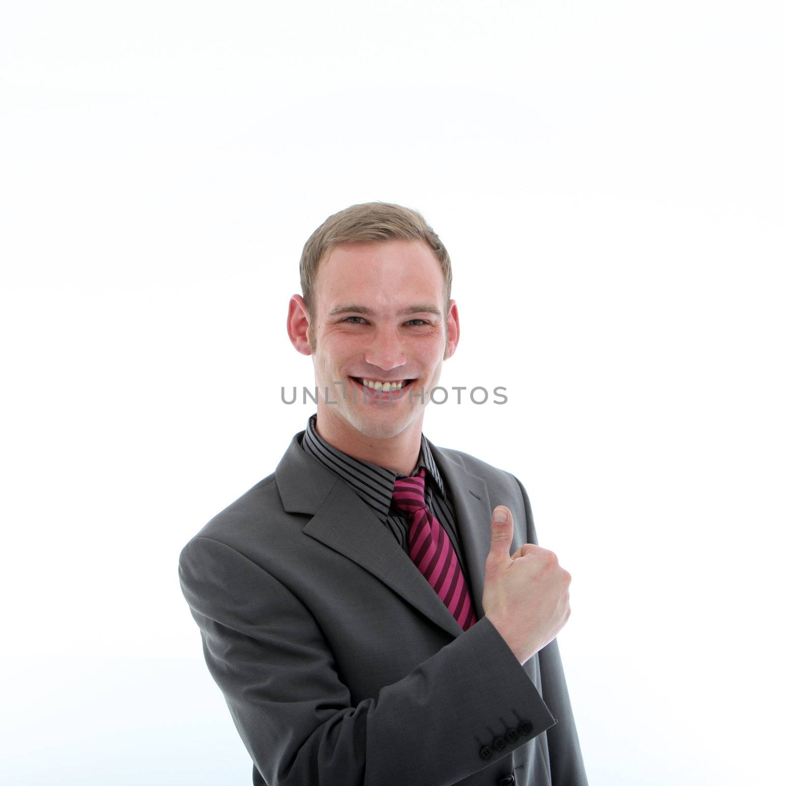 Handsome confident businessman with a broad grin giving a thumbs up gesture of success isolated on white