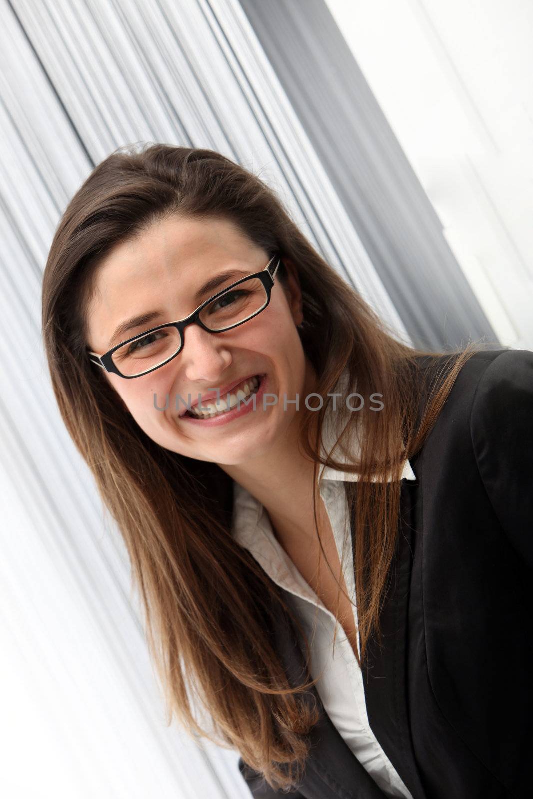 Smiling young professional woman in glasses looking into the camera, angled studio portrait